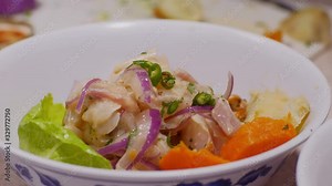 Slow motion video of serving Peruvian Ceviche in a bowl, with sweet potatoes, over lettuce, and topped with toasted Peruvian corn