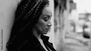 One desperate middle-aged woman struggles with depression while standing outside in urban street during hard times, person in crisis feeling despair and anxiety captured in black and white