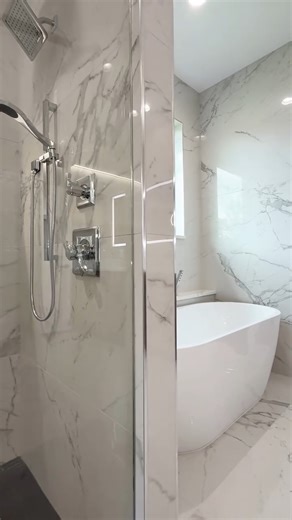 MSI Surfaces on Instagram: "Calacatta Isla Porcelain Tile adds classic marble style to this bathroom, flowing seamlessly across the floor and walls. With subtle veining, cool white tones, and multiple format options, it’s a versatile choice for modern and traditional designs alike. Credit: @curingtonhomes @kaitlynloosdesign"