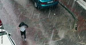 Unrecognised man going street under heavy rain in the European city
