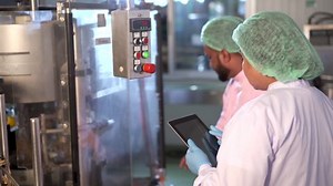 Team of senior professional quality control officer inspecting the manufacturing line and computer system in the beverage bottling factory.