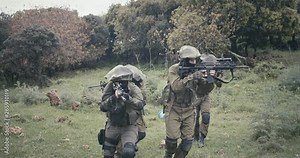 Squad of fully armed commando soldiers during combat in a forest scenery