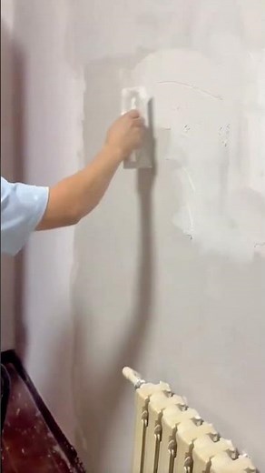 A person is spreading wall putty using a trowel