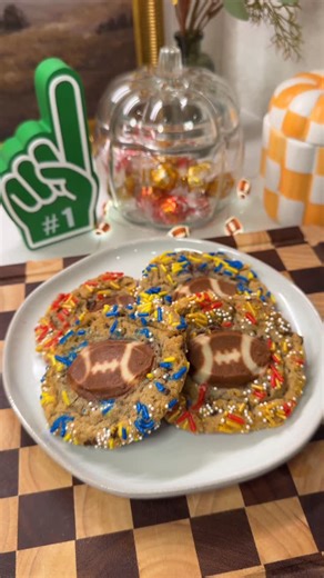 Jenn Ordway on Instagram: "Easiest double layer football cookies for game day! 🏈 Can you tell what teams we like in this house? 💙💛❤️💛 Recipe: * Take chocolate chip cookie dough and form into balls * Roll in colored sprinkles for your team of choice * Bake at 350F for 5 minutes * Take out and top with @pillsbury football cookies * Bake for another 10 minutes at 350 and enjoy! #asmrfood #footballcookies #footballsnacks #footballfood #gamedayfood #gamedaysnacks #game