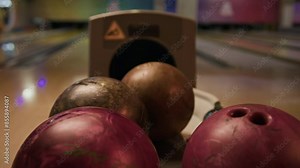 No people closeup with slowmo of bowling ball coming out from hole in rack with other colored balls