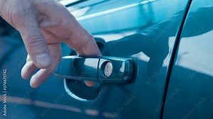 A man, a driver, a buyer opens the driver's seat door by the key, gets behind the steering wheel of a new blue car and closes the door, then gets out of the car and closes the door by the key. Closeup