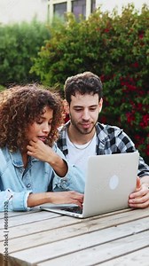 Collaborative multi-ethnic students working on laptop at campus outdoor. Diverse students collaborate on a laptop outdoors at campus, engaging in teamwork and group projects