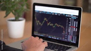 4k resoltuion of man working on a laptop, with financial charts displayed. Businesss man at a computer, indoors shot.