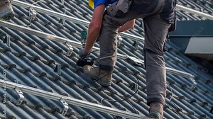 Worker Attaches Wire Box to Solar Panel Railing Mounts on Roof
