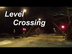Level crossing with barriers - trains in snow at night