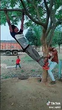 A boy tied to a tree in a funny way