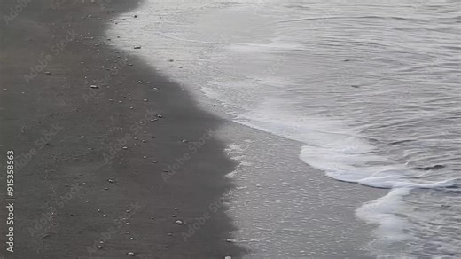 Sandy beach with small stones and waves of sea - natural background. Topics: vacation, rest, travel, peace, relaxation, natural environment