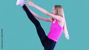 Cute joyful girl practices gymnastics in the sport school, she stretches, splits standing on one leg and shows a hand gesture V, proving her success. Isolated on blue background.