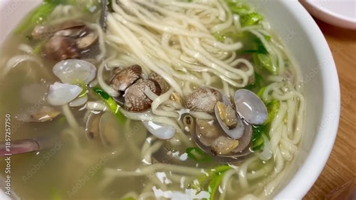 Close-up of Korean clam noodle soup, Bajirak-kalguksu, with fresh clams and handmade noodles in a savory broth.