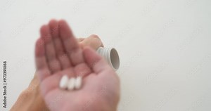 Man pouring magnesium pills from a plastic bottle into his palm and taking them. Close up.