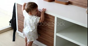 Baby standing on home furniture learning to stand, child infant development leaning on table
