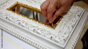 Repair of the antique picture frame by restorer, work with gaps in angles, using putty and gilt to renovate the nice look of old wooden decor.