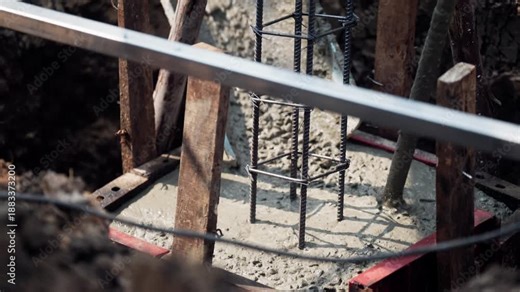 Close-up view of concrete pad foundation recently poured with steel rebar reinforcement, used in residential and commercial building construction.