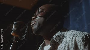 Young Black comedian talking in microphone in microphone in stage during stand-up comedy performance. Close-up view