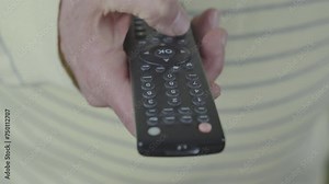 Old male person holding aged remote control in hand and switch off and on television channels during tv set watching close up