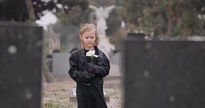 Child Holding Flower in Cemetery