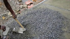 Indian mason worker pouring water over cement mix to ensure proper hydration for construction