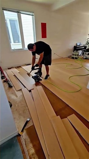 Man Installing New Laminate or Hardwood Flooring in a Home Living Area, Using a Floor Nailer Tool