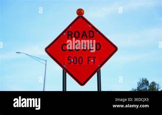 Road closed sign with orange warning color on street. Traffic restriction and construction safety. High quality 4k footage Stock Video Footage - Alamy