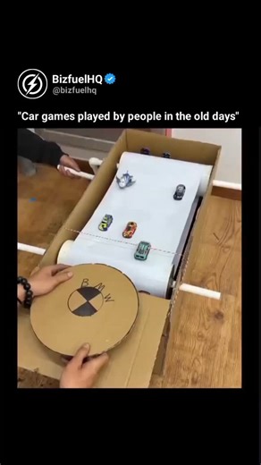 BizfuelHQ on Instagram: ""Car games played by people in the old days" The video features a clever DIY racing simulator crafted from cardboard, PVC pipes, and toy cars, utilizing a manual conveyor belt to mimic a moving highway. One person operates a hand-crank to rotate the paper "road" while the player navigates a cardboard steering wheel to dodge obstacles, showcasing an ingenious mechanical design that functions entirely without electricity. Posted by @ sciencegirl on January 28, 2026, this r
