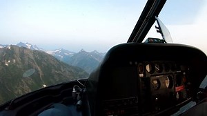 Helicopter cockpit view of Canadian Rocky mountain Heli hikers being flown to drop of destination near glacial lake British Columbia RED MONSTRO