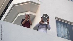 Young couple clapping and banging the utensils to appreciate and salute the essential service providers,health workers,police,nurses,paramedical staff,doctors etc in pandemic.flash mob in lock down