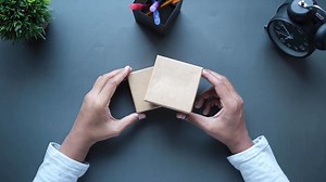 Overhead view of woman opening a small brown gift box