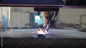 A plasma cutter making patterns from the metal sheet. The cutter drawing some curve lines on the metal sheets