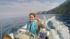 Cool Girl driving speed boat through ocean on wild travel adventure freedom peace sign vacation