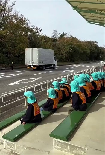 Japanese kids learn road safety through immersive, fun, hands-on methods like mini driving courses with go-karts, real truck driver demos, mascots, and practicing the iconic "hand-raise" crossing, building awareness of blind spots and traffic rules for safe pedestrian habits in a country where cars drive on the left
