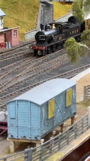 Welcome to Staindrop, a beautiful 7mm O gauge layout by Chris Robertson, set in the South West Durham countryside circa 1928. This layout imagines a 'might have been' branch of the London and North Eastern Railway (LNER), showcasing steam railcars and the pre-grouping character of the North Eastern Railway (NER). See the detailed station building based on Battersby, the water tank from Middleton-in-Teesdale, and the wooden overbridge from the Stainmore line. Discover the coal cells, cattle, hors