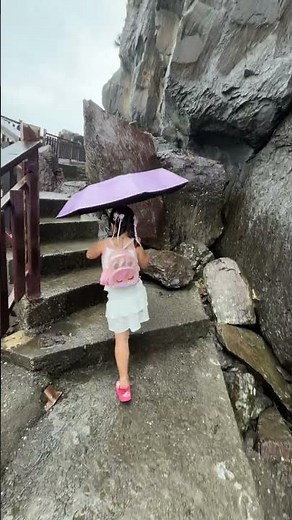 Rainy Coastal Rock Trail Footage: Girl with Umbrella Walking Along Path.