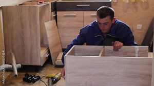 assembling kitchen furniture,a young furniture assembler is assembling the kitchen