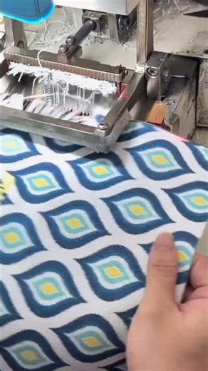 weaving a patterned fabric with an industrial loom machine in an indoor textile factory area