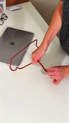 Reshaping red wire hanger on creative workspace desk