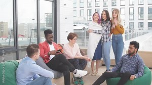 Lounge outdoor zone at modern office. People discussung working process sitting on soft poufs over glass urban skyscrapers background