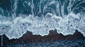 Video aerial view of ocean waves foam rolling into beach shoreline, sea surf tide crashing into the beach
