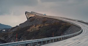 Storseisundet bridge on the Atlantic road rises above the landscape. Heavy clouds in the sky. Seagul