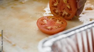 Slow motion, close up on a round slice of a tomato.