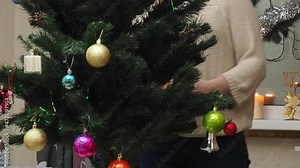 Family decorating a Christmas tree with boubles in the living room. mom and daughter decorate the tree with different toys home, family holidays, happy new year and christmas