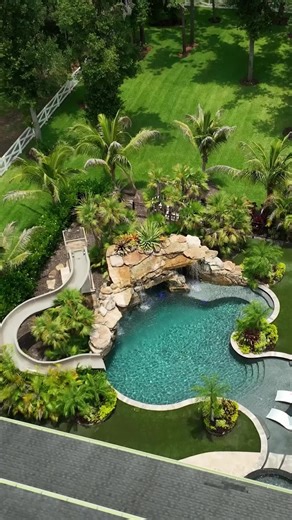 This backyard has a huge grotto, a waterslide, a big elevated spa with a swim-up bar, a sun shelf area, and a big swimming and jumping play area. This place is laid out for entertaining. #insanepools #lucaslagoons #pool #poolbuilders #backyard