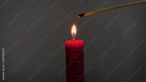 Single pink candle burning. Shot. Isolated on dark background candle burning. The match lights from candle. Concept of attention, mutual assistance and mentoring