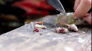 Slow motion , Close up fisherman's hand working using knife cleaning and filleting small fish on old rusty chopping board