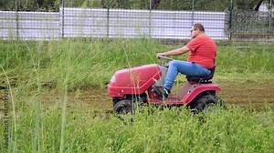 Gardener driving lawn tractor across villa lawn