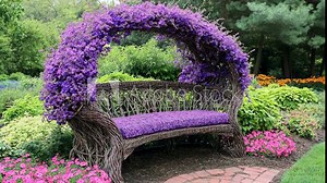 A wicker bench sits under a beautiful arch of purple flowers in a lush garden
